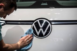 An employee polishes a Volkswagen logo on an I.D. Buzz before the annual press conference presenting VW's full 2022 financial results. Photo: Michael Kappeler/dpa