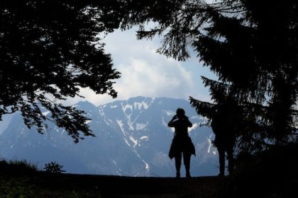 A hiker photographs the panoramic view of the German alps near Pfronten. The German Alps had fewer visitors at the start of this year than before the coronavirus pandemic. Photo: picture alliance / Karl-Josef Hildenbrand/dpa