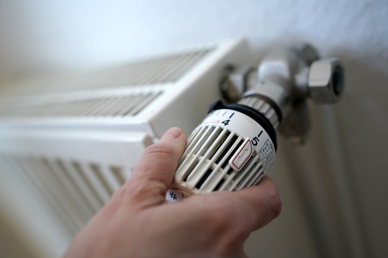 A woman turns a heating thermostat. Photo: Marcus Brandt/dpa