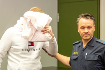 The nurse (L), accused of murdering two patients, is brought into the courtroom at the beginning of the trial and holds a bag in front of his face at the Munich I Regional Court. Photo: Lennart Preiss/dpa