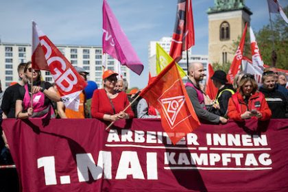 Participant hold flags in front of the Red City Hall during a demonstration of the German Trade Union Confederation (DGB) under the slogan "Unbroken solidarity" on May Day. Photo: Hannes P. Albert/dpa