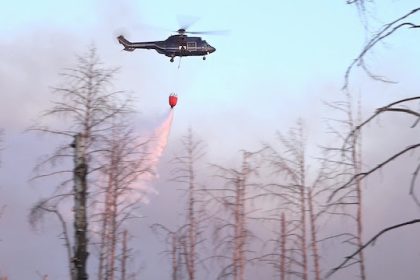 A firefighting helicopter drops water over a forest fire in an area contaminated by munitions near Jueterbog. The forest fire has spread to around 27 hectares despite the aerial firefighting efforts. Photo: Cevin Dettlaff/dpa