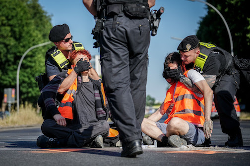 Police officers remove members of the Last Generation from the street during a blockade at the Great Star at the Victory Column. Photo: Kay Nietfeld/dpa