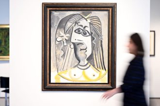 An employee of the auction house Van Ham walks past the painting "Buste de femme" from 1971 by Pablo Picasso. Photo: Federico Gambarini/dpa