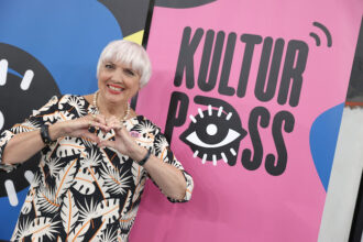 Claudia Roth, German Culture Minister, stands in front of the "Culture Pass" logo. Photo: Jörg Carstensen/dpa